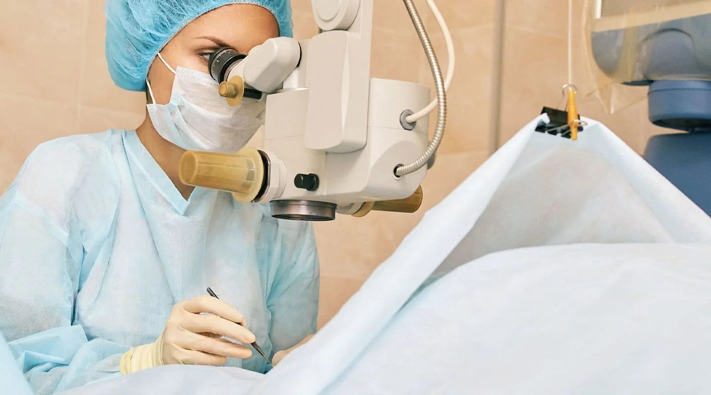 Cirurgiã oftalmologista operando com microscópio cirúrgico em centro cirúrgico